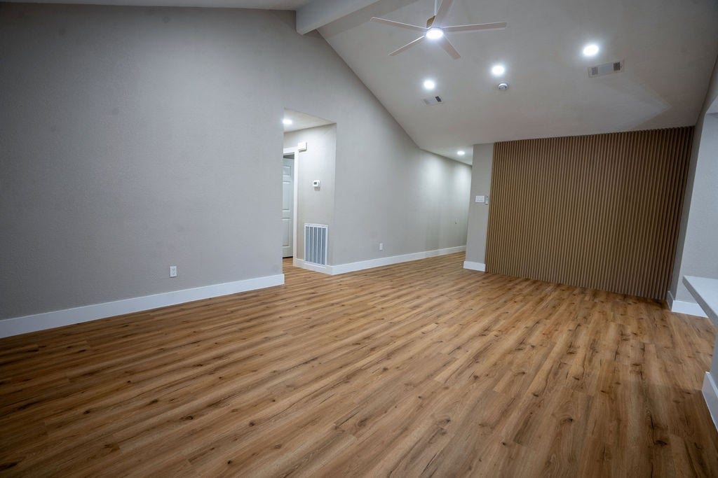 9856 Oriole, Conroe, TX 77385 Spacious living area featuring sleek wood style flooring, modern recessed lighting, and a stylish accent wall, perfect for comfortable living and entertainment.