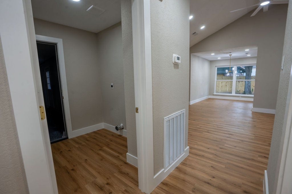 9856 Oriole, Conroe, TX 77385 Bright and inviting hallway with elegant wood style flooring leads to a spacious living area featuring large windows and recessed lighting.
