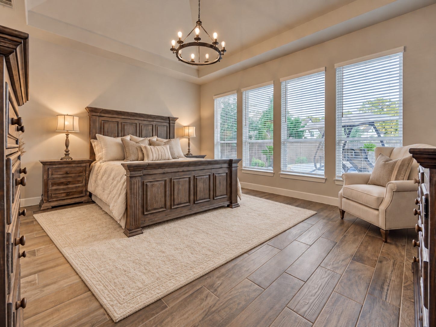 305 Pewter Sky Drive, Montgomery, TX 77316 Spacious primary retreat filled with natural light from a wall of windows overlooking the backyard oasis. A dramatic tray ceiling, statement chandelier and wood-look tile flooring elevate the space, while double doors open to the private en-suite bath.