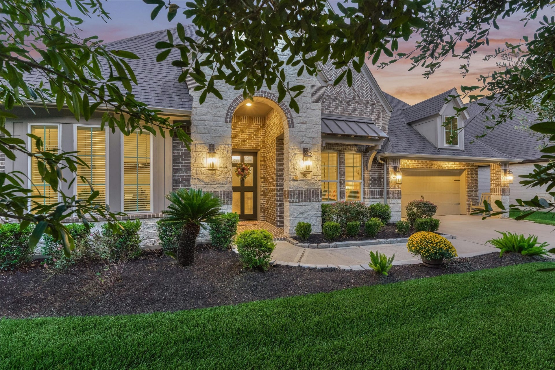 305 Pewter Sky Drive, Montgomery, TX 77316 A grand arched entry, upgraded exterior lighting and layered architectural details add depth and dimension to the striking front elevation, beautifully complemented by rich brick, stone and manicured landscaping.