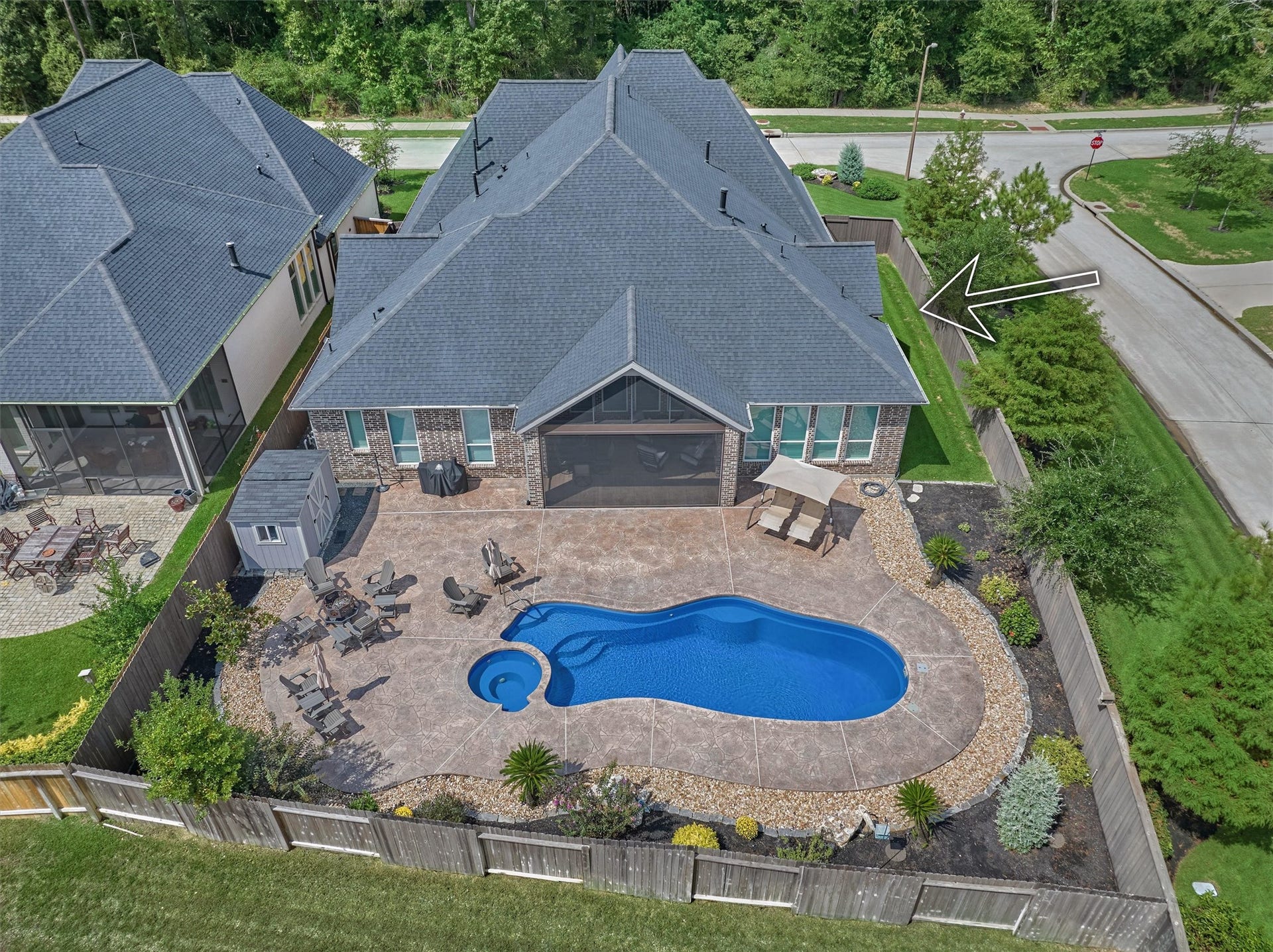 305 Pewter Sky Drive, Montgomery, TX 77316 Resort-style backyard retreat featuring a sparkling pool with integrated hot tub, expansive stamped concrete decking, lush landscaping and an extended covered patio with screen enclosure including electronic remote opening.