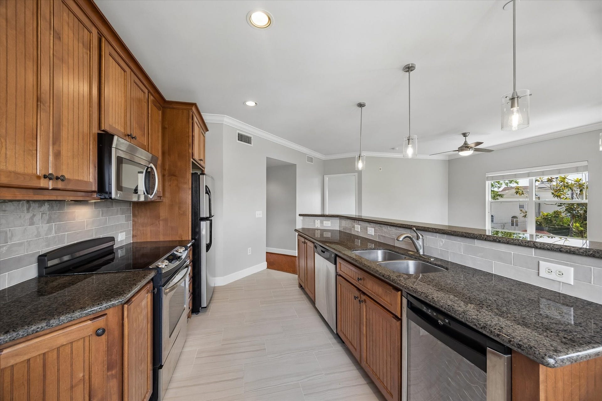 2203 Dorrington Street Street, #205, Houston, TX 77030 This kitchen features modern stainless steel appliances, new kitchen faucet, granite countertops, and elegant wood cabinetry. It has a sleek open layout with updated pendant lighting and a breakfast area with direct access to the balcony, offering a bright, inviting atmosphere.