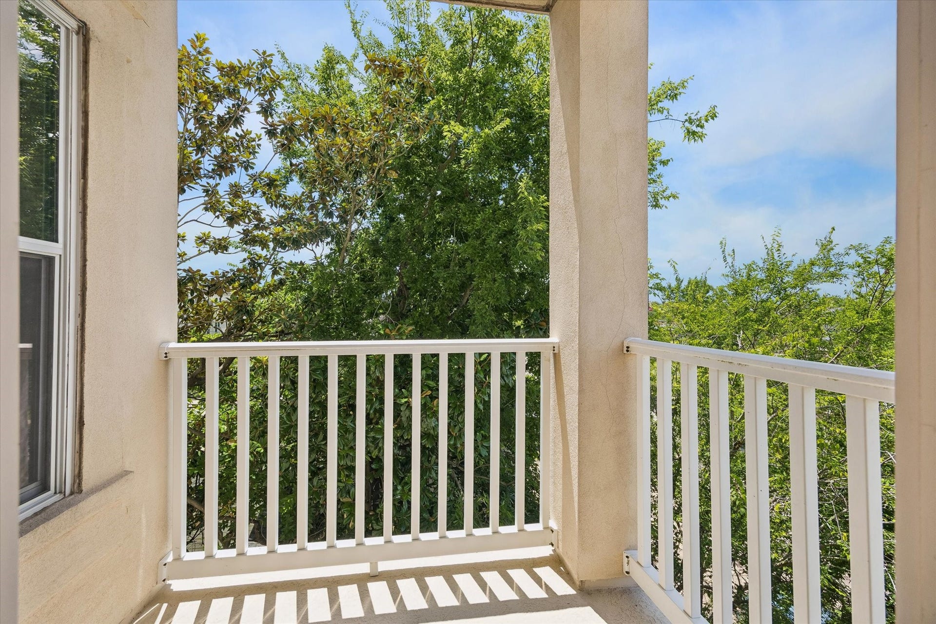 2203 Dorrington Street Street, #205, Houston, TX 77030 Bright, cozy balcony with white railings, offering a serene view of lush green trees and since this is a corner unit you have unobstructed views. Perfect for relaxation.