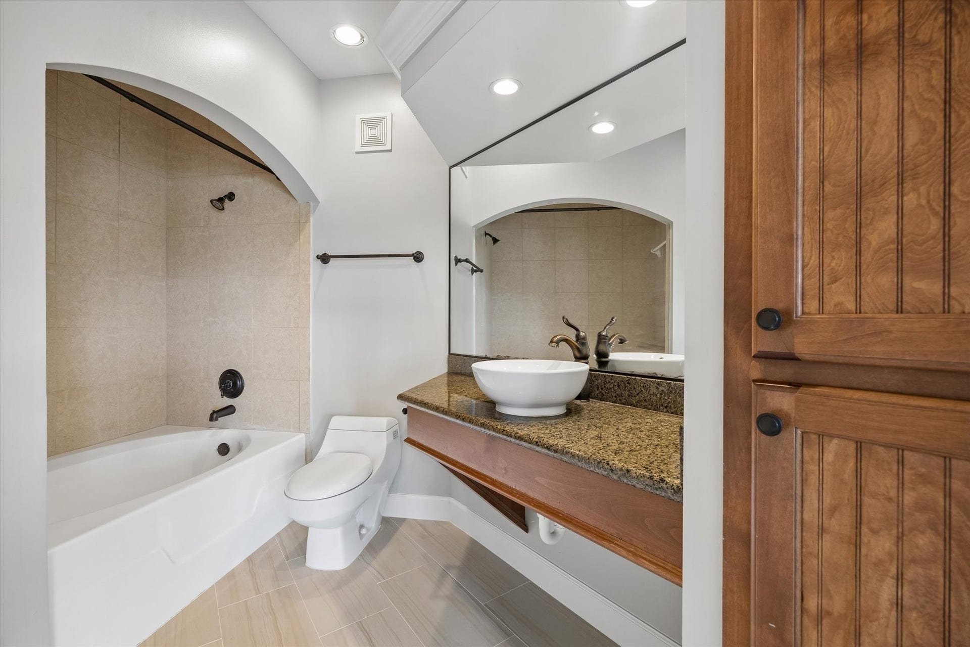 2203 Dorrington Street Street, #205, Houston, TX 77030 The spacious en suite primary bathroom features a modern design with a combination shower/ bathtub, recessed lighting, new toilet and warm wooden cabinetry for a cozy yet elegant feel.