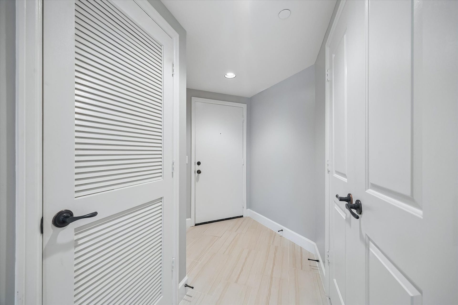 2203 Dorrington Street Street, #205, Houston, TX 77030 This photo shows a bright, modern entryway with light floors and soft gray walls. It features white doors with black hardware, creating a clean, contemporary look.