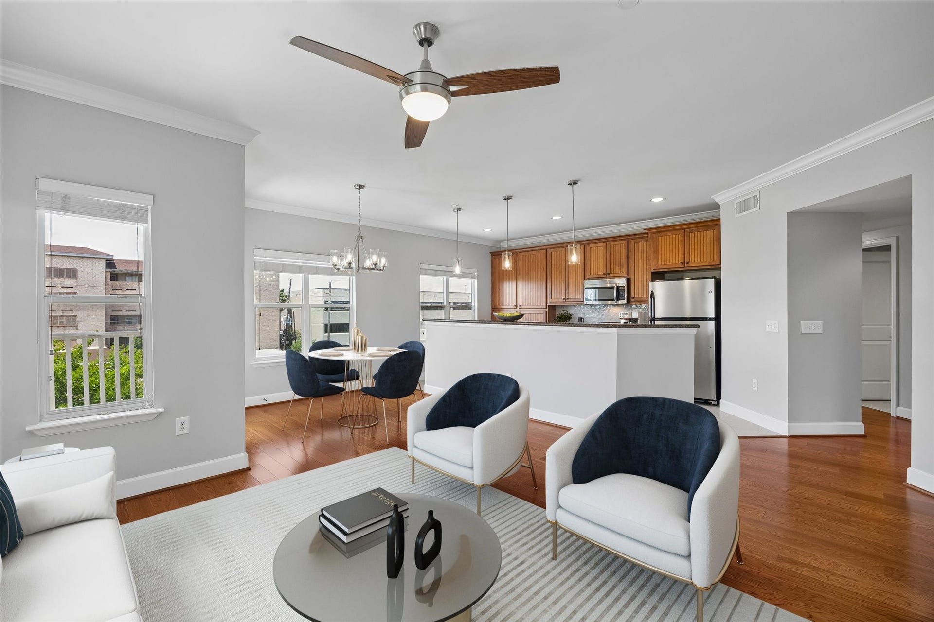 2203 Dorrington Street Street, #205, Houston, TX 77030 This photo showcases a modern open-concept living space with light gray walls and beautiful floors. It features a cozy seating area, a dining space with a stylish chandelier that was recently updated and a kitchen with stainless steel appliances and wooden cabinetry. Natural light floods the room through large windows, creating a bright and inviting atmosphere.