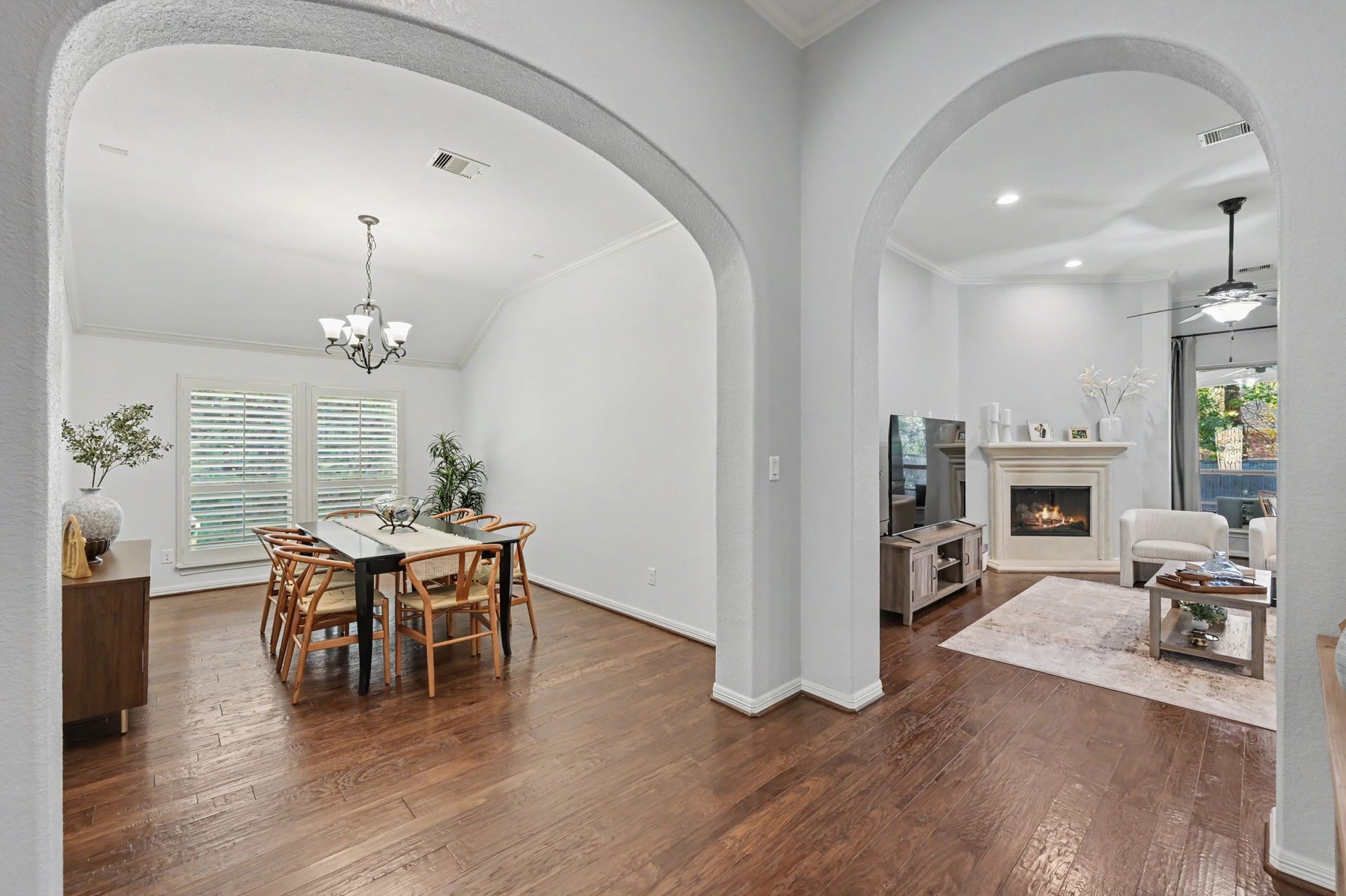 271 Rio Ranch Circle, Montgomery, TX 77316 Elegant open-concept living and dining area featuring beautiful hardwood floors, graceful archways, and a cozy fireplace, perfect for entertaining and relaxation.