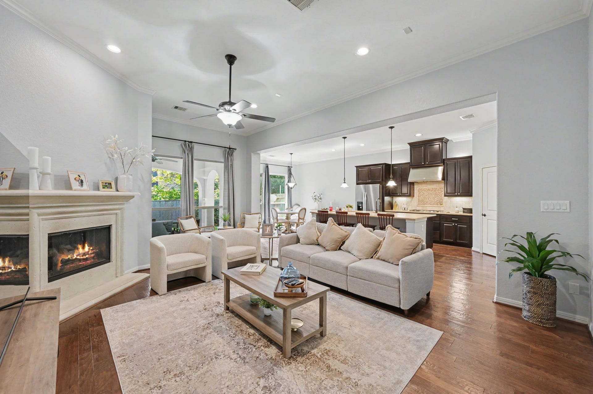 271 Rio Ranch Circle, Montgomery, TX 77316 Spacious open-concept living area with a cozy fireplace, elegant hardwood floors, and seamless flow into a modern kitchen featuring dark cabinetry and a breakfast bar.