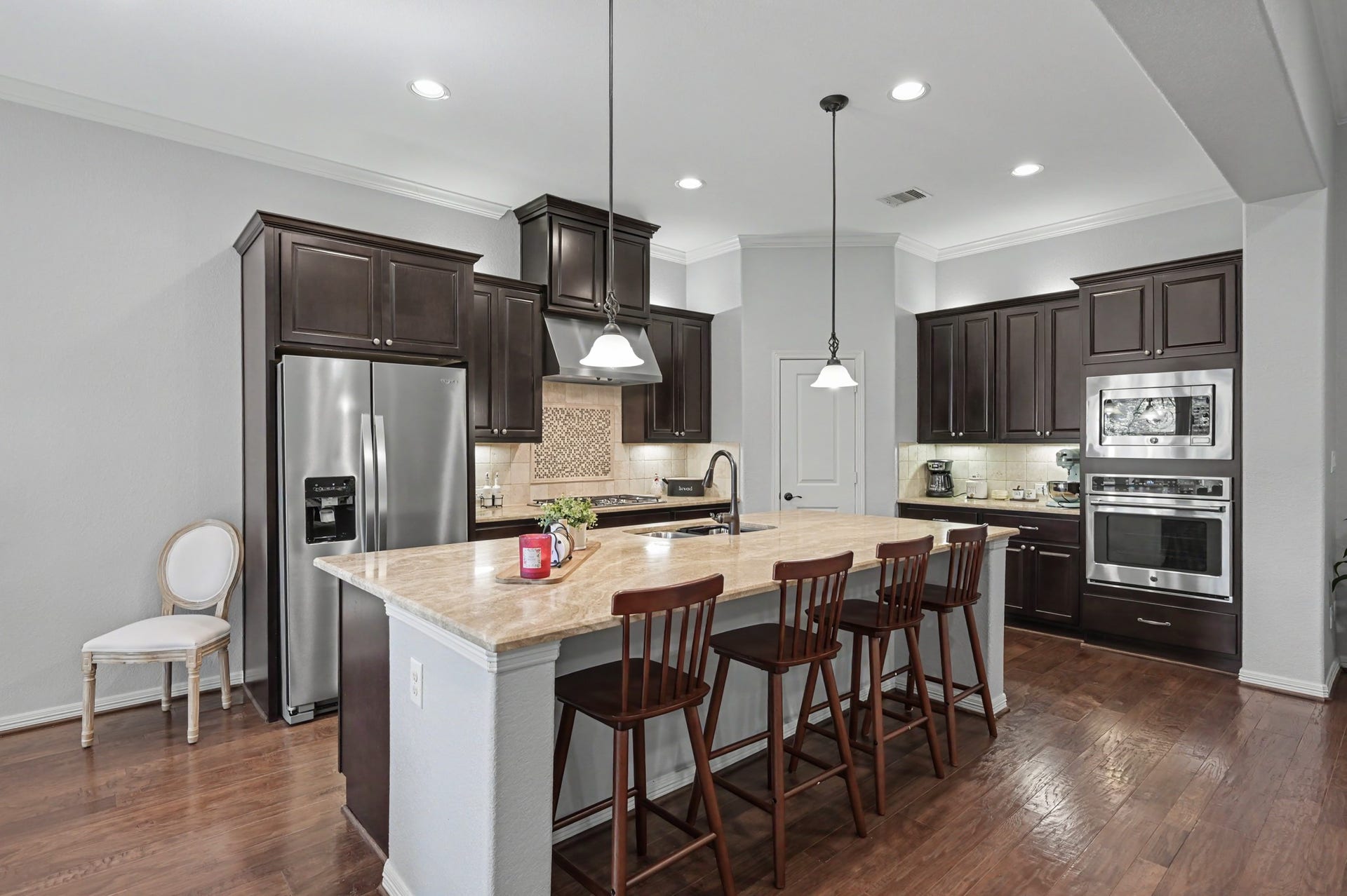 271 Rio Ranch Circle, Montgomery, TX 77316 Elegant kitchen featuring rich dark wood cabinets, stainless steel appliances, and a spacious island with seating, perfect for entertaining.