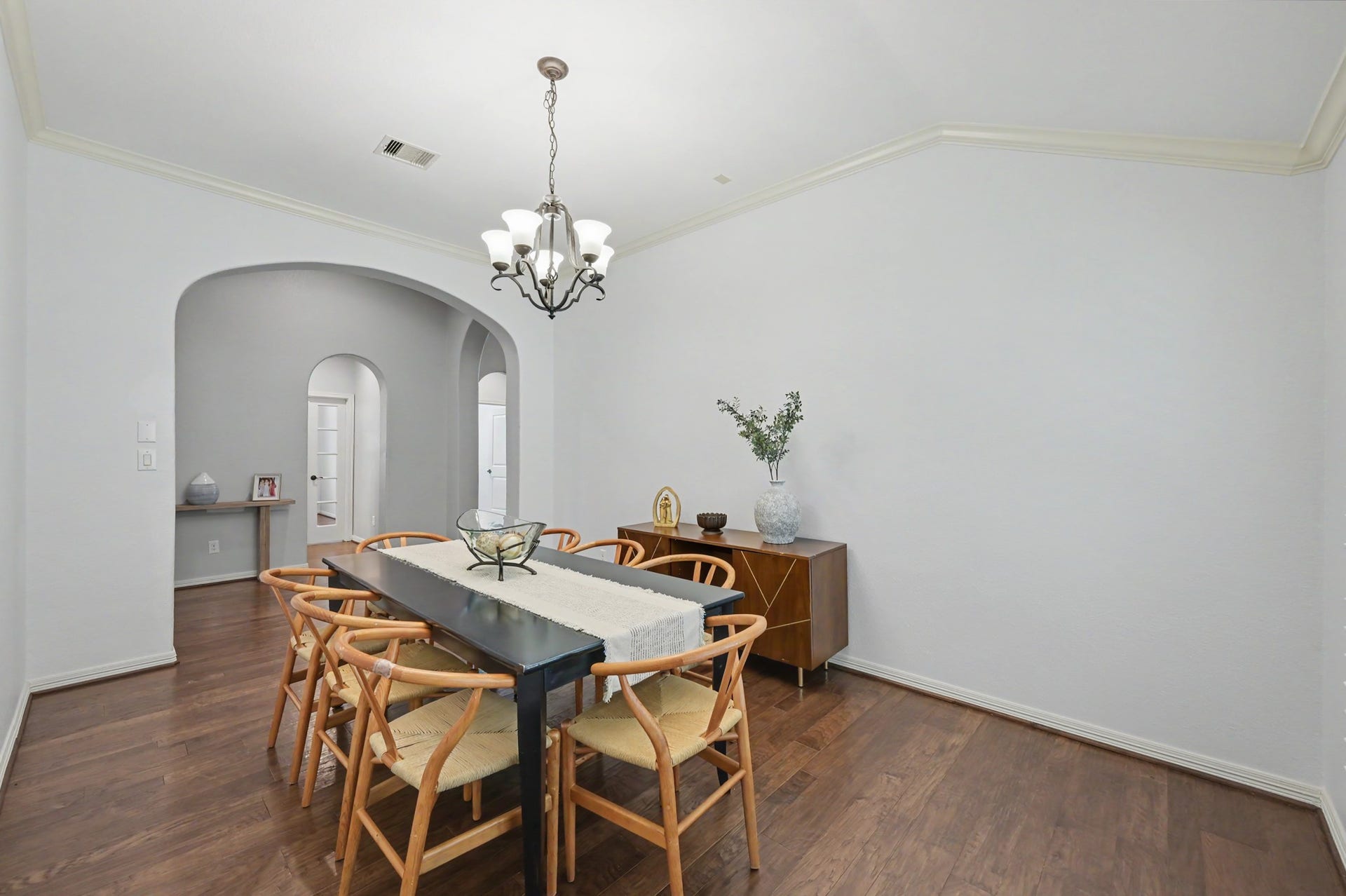 271 Rio Ranch Circle, Montgomery, TX 77316 Elegant dining room with a sleek black table, surrounded by stylish wooden chairs, under a chic chandelier. Soft archways and light walls create an inviting ambiance.