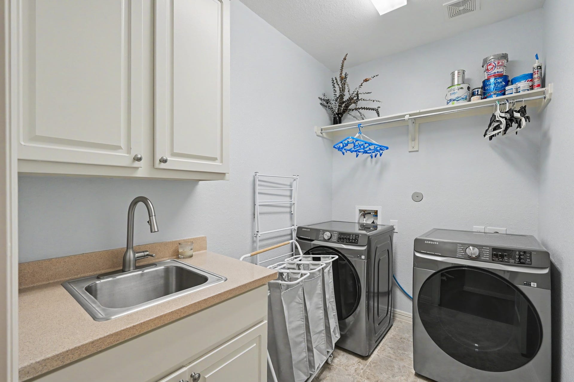 271 Rio Ranch Circle, Montgomery, TX 77316 Modern laundry room featuring sleek front-loading washer and dryer, ample cabinetry, and a convenient utility sink for added functionality.