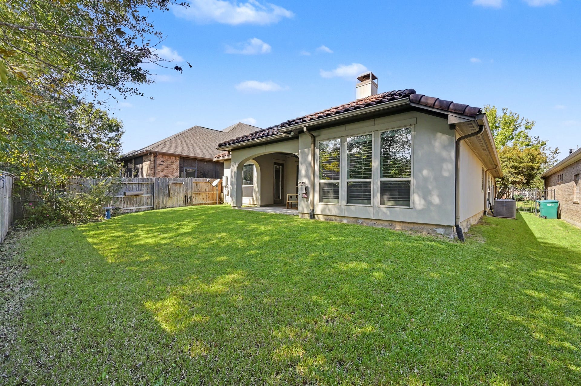 271 Rio Ranch Circle, Montgomery, TX 77316 Charming backyard with lush green lawn, perfect for outdoor activities, complemented by a cozy patio with arched openings for relaxation.