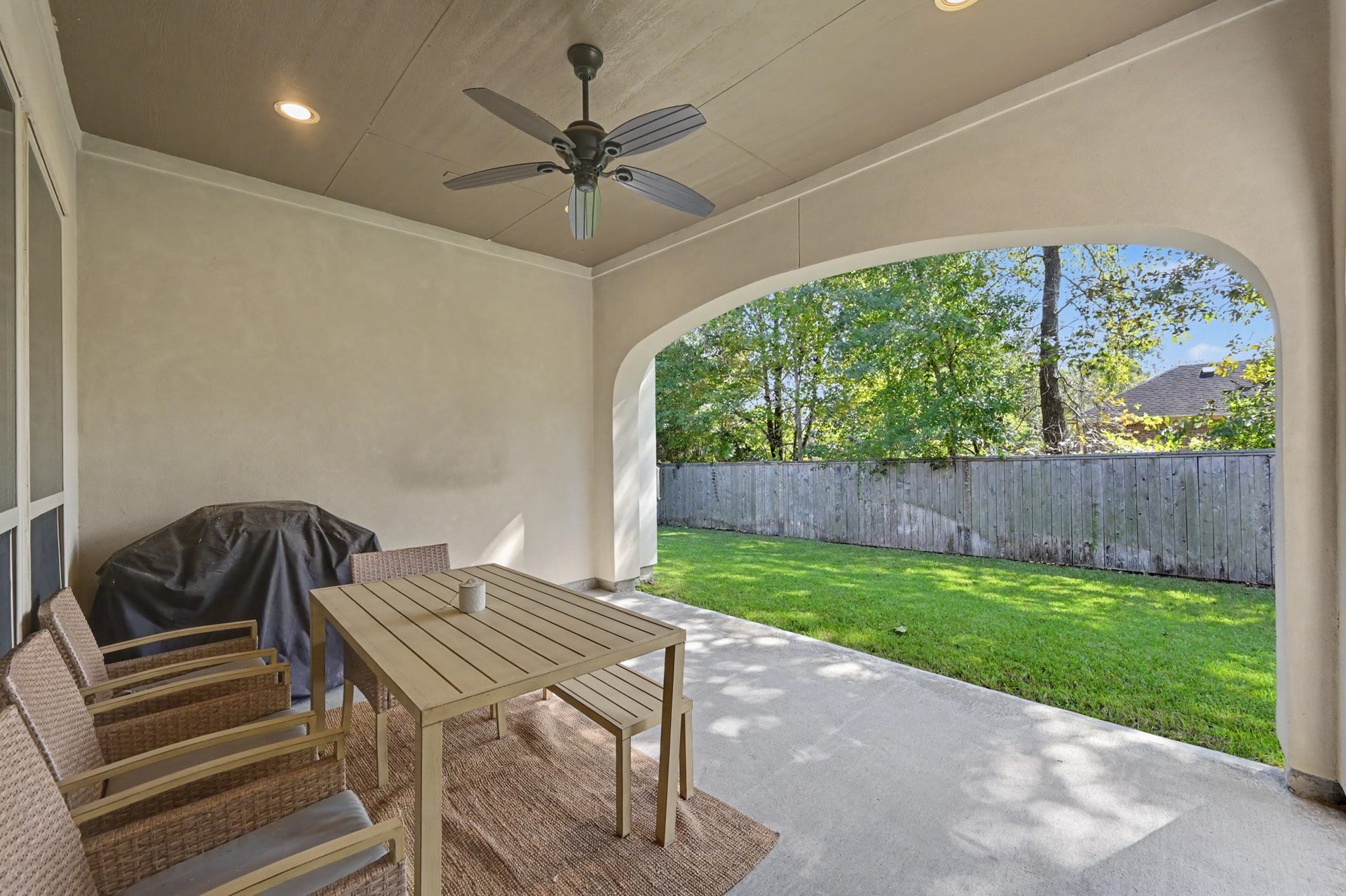271 Rio Ranch Circle, Montgomery, TX 77316 Charming covered patio with ceiling fan, perfect for outdoor dining and relaxation, overlooking a private, fenced backyard with lush greenery.