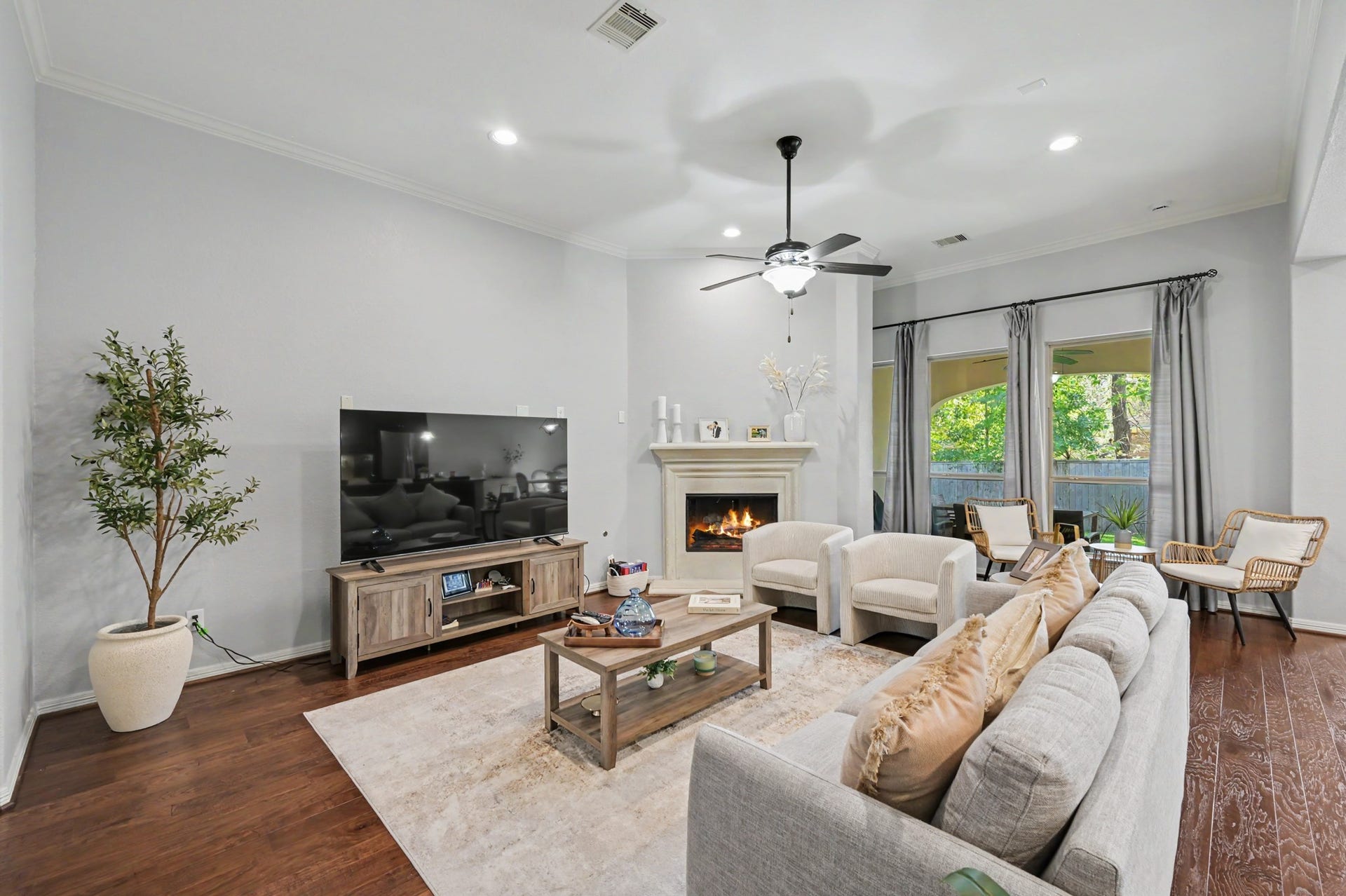 271 Rio Ranch Circle, Montgomery, TX 77316 Charming living room with a cozy fireplace, elegant ceiling fan, and large windows offering natural light. Comfortable seating and stylish decor create a welcoming atmosphere.