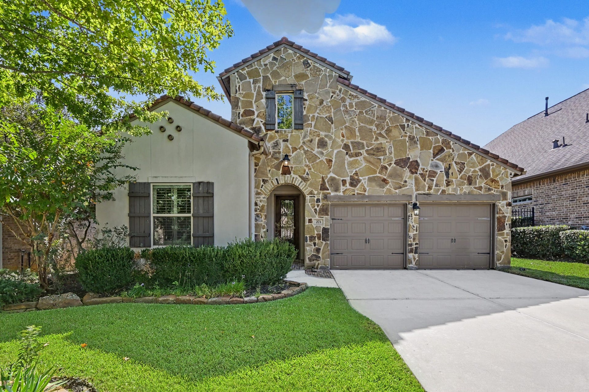 271 Rio Ranch Circle, Montgomery, TX 77316 Charming home with a stunning stone facade and cozy shutters, complemented by a well-maintained lawn and lush landscaping.
