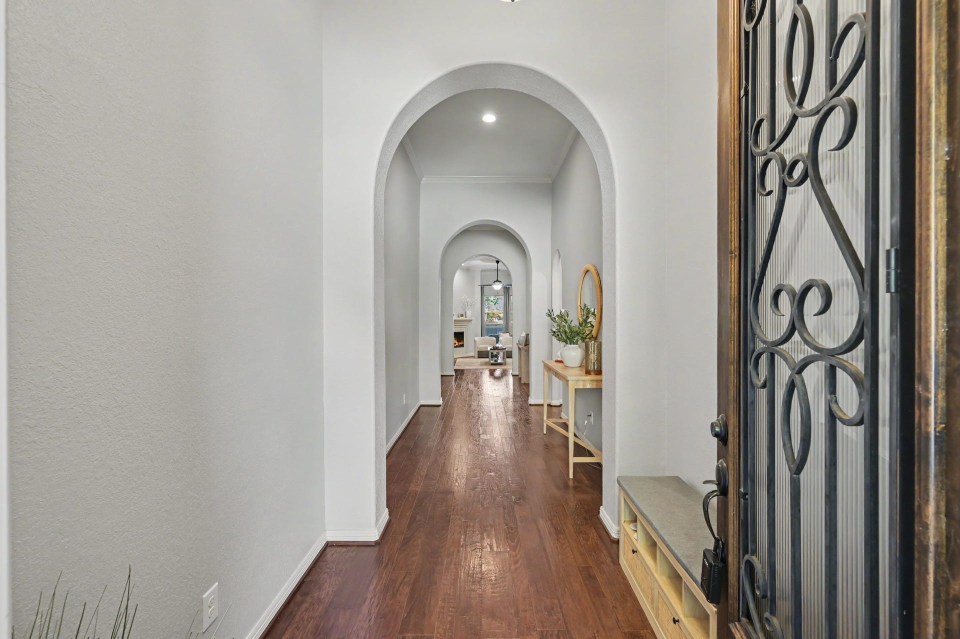 271 Rio Ranch Circle, Montgomery, TX 77316 Inviting entryway with elegant arched doorways and warm hardwood floors, leading to a cozy and well-lit living area.