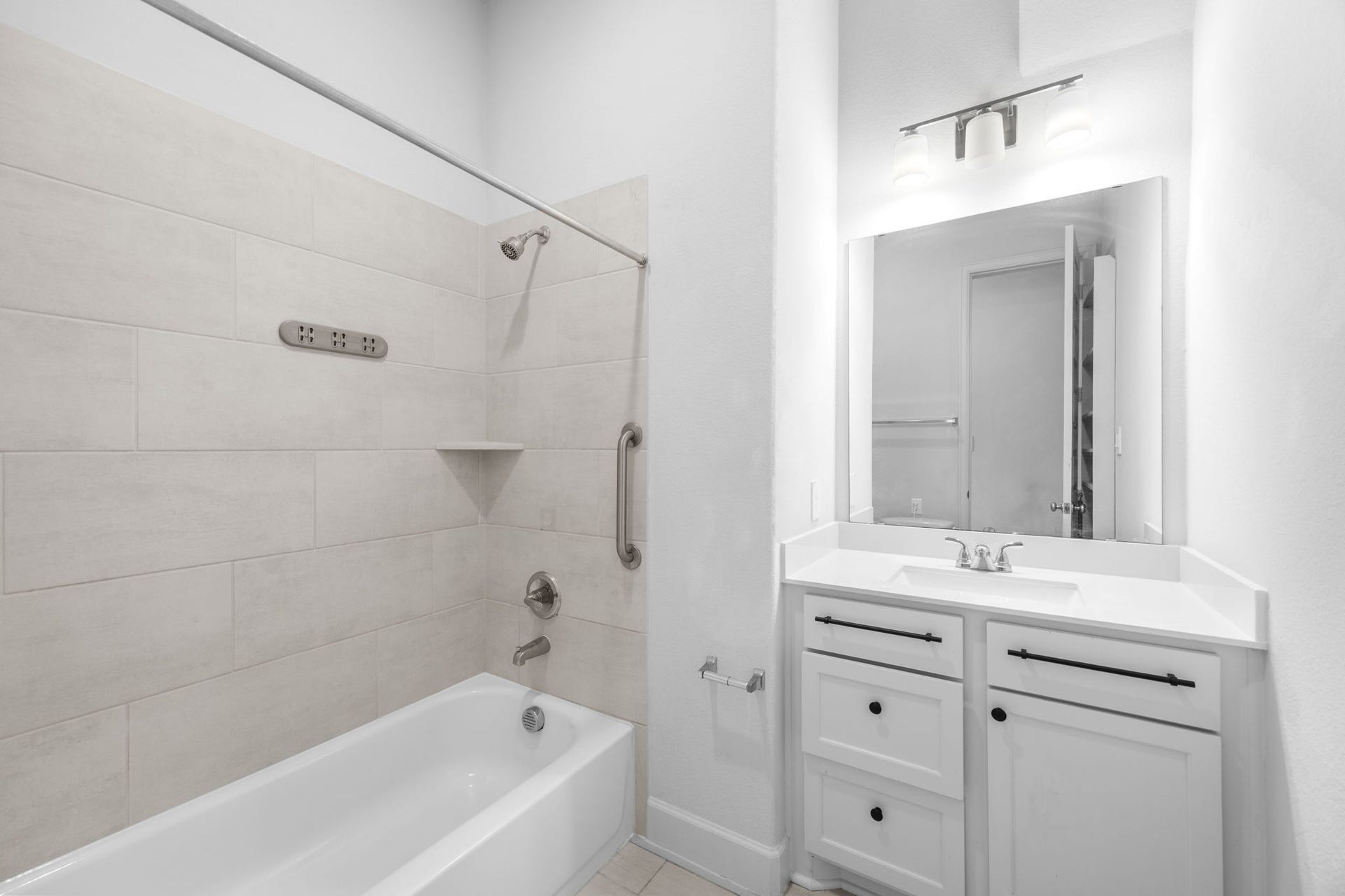 726 Fall Rock Branch Drive, Conroe, TX 77304 Stylish secondary bathroom with a tub and shower combination, beautiful tilework, and ample vanity storage.