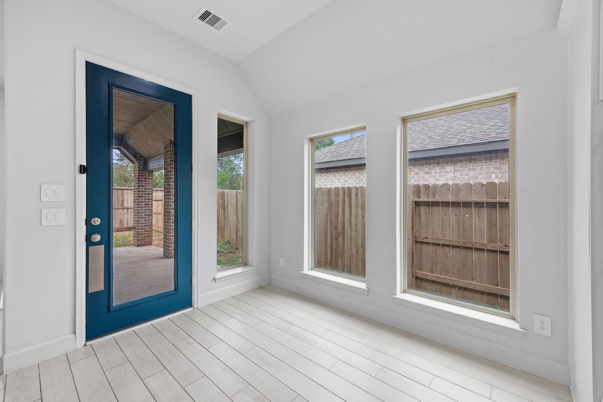 726 Fall Rock Branch Drive, Conroe, TX 77304 Charming breakfast area with expansive windows and a striking blue-framed glass door.