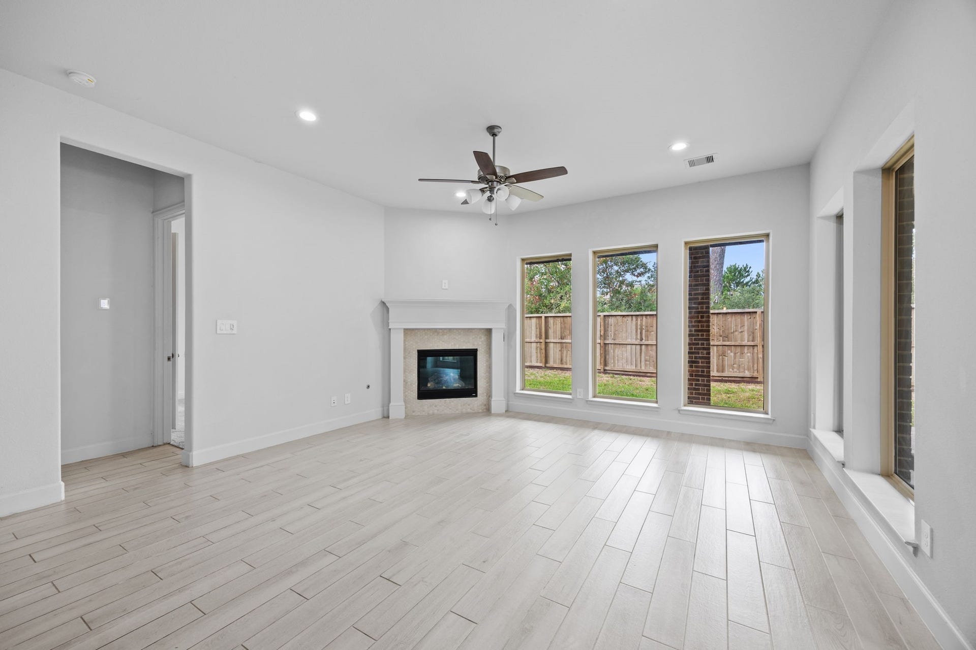726 Fall Rock Branch Drive, Conroe, TX 77304 Inviting living space with a fireplace, ceiling fan, and picturesque backyard views.