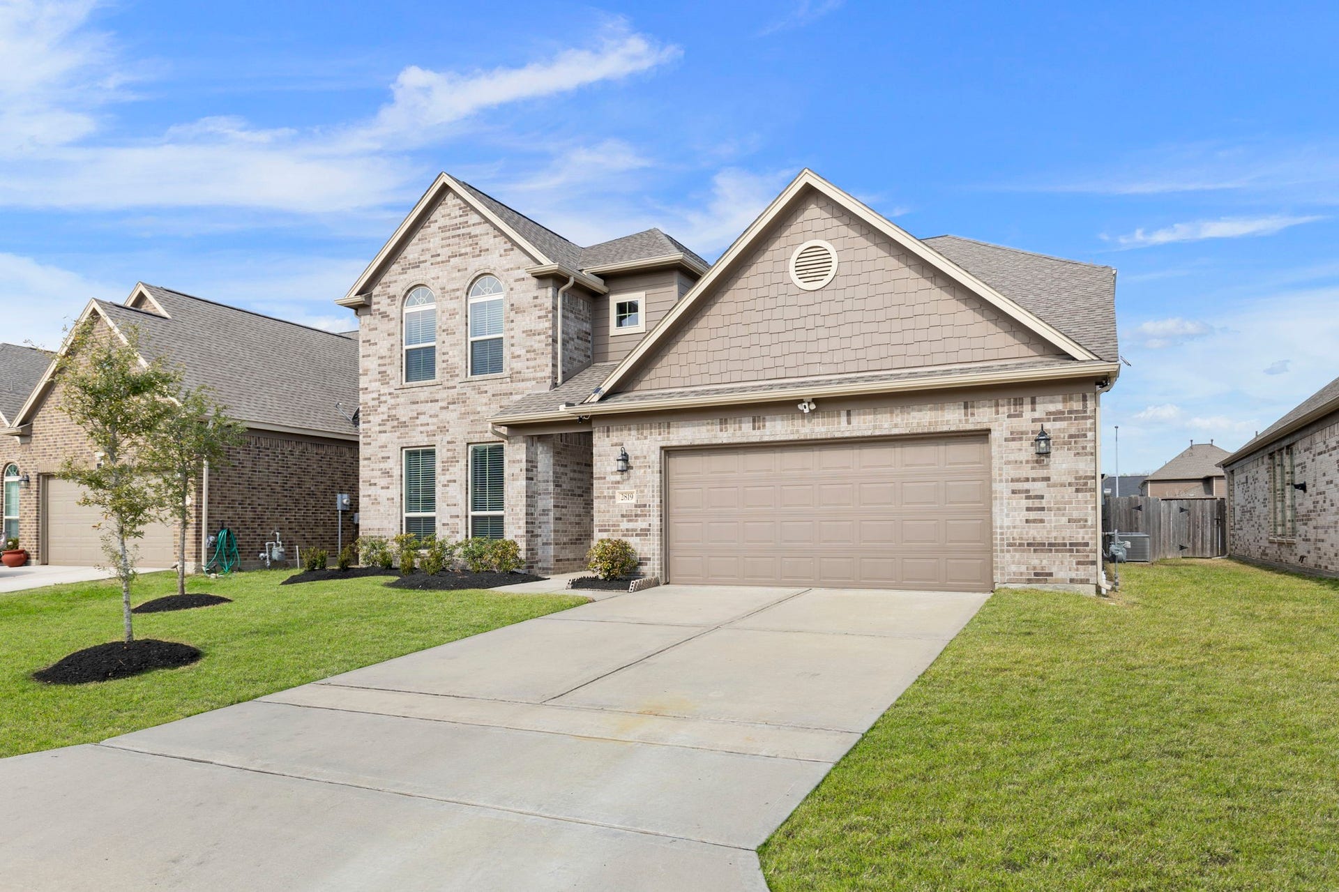2819 Bradbury Hills Drive, Spring, TX 77373 This is a two-story brick home with a gabled roof, featuring a spacious two-car garage. The front yard is well-maintained with a small tree and clean landscaping. The exterior has a mix of brick and siding, offering a modern and inviting look.