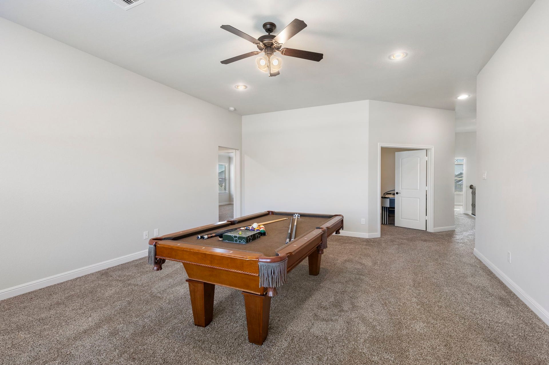 2819 Bradbury Hills Drive, Spring, TX 77373 Spacious recreational room with a pool table, neutral carpeting, and a ceiling fan. It features ample lighting and access to adjacent rooms, creating an inviting entertainment space.