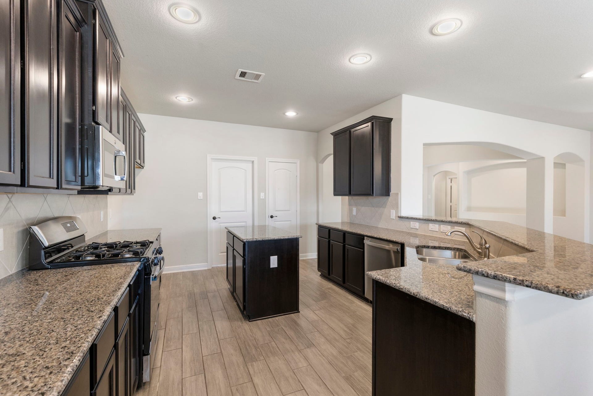 2819 Bradbury Hills Drive, Spring, TX 77373 This modern kitchen boasts sleek dark cabinetry, polished granite countertops, and stainless steel appliances, creating an inviting space perfect for culinary adventures and gatherings.