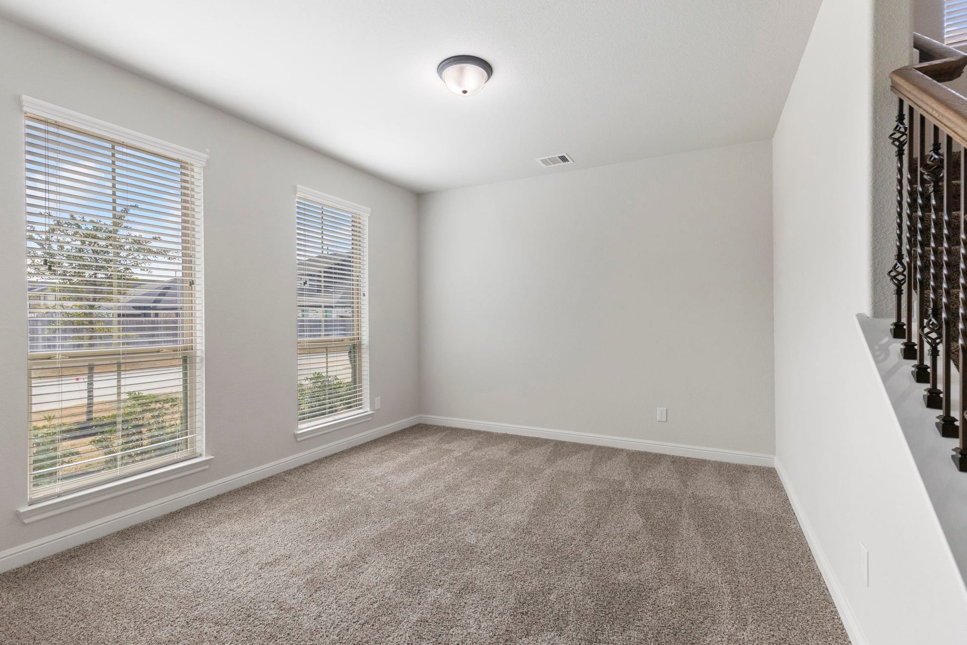 2819 Bradbury Hills Drive, Spring, TX 77373 Discover a bright and inviting living/seating room featuring plush carpet, abundant natural light from large windows, and a stylish railing accent, perfect for relaxation and entertaining.
