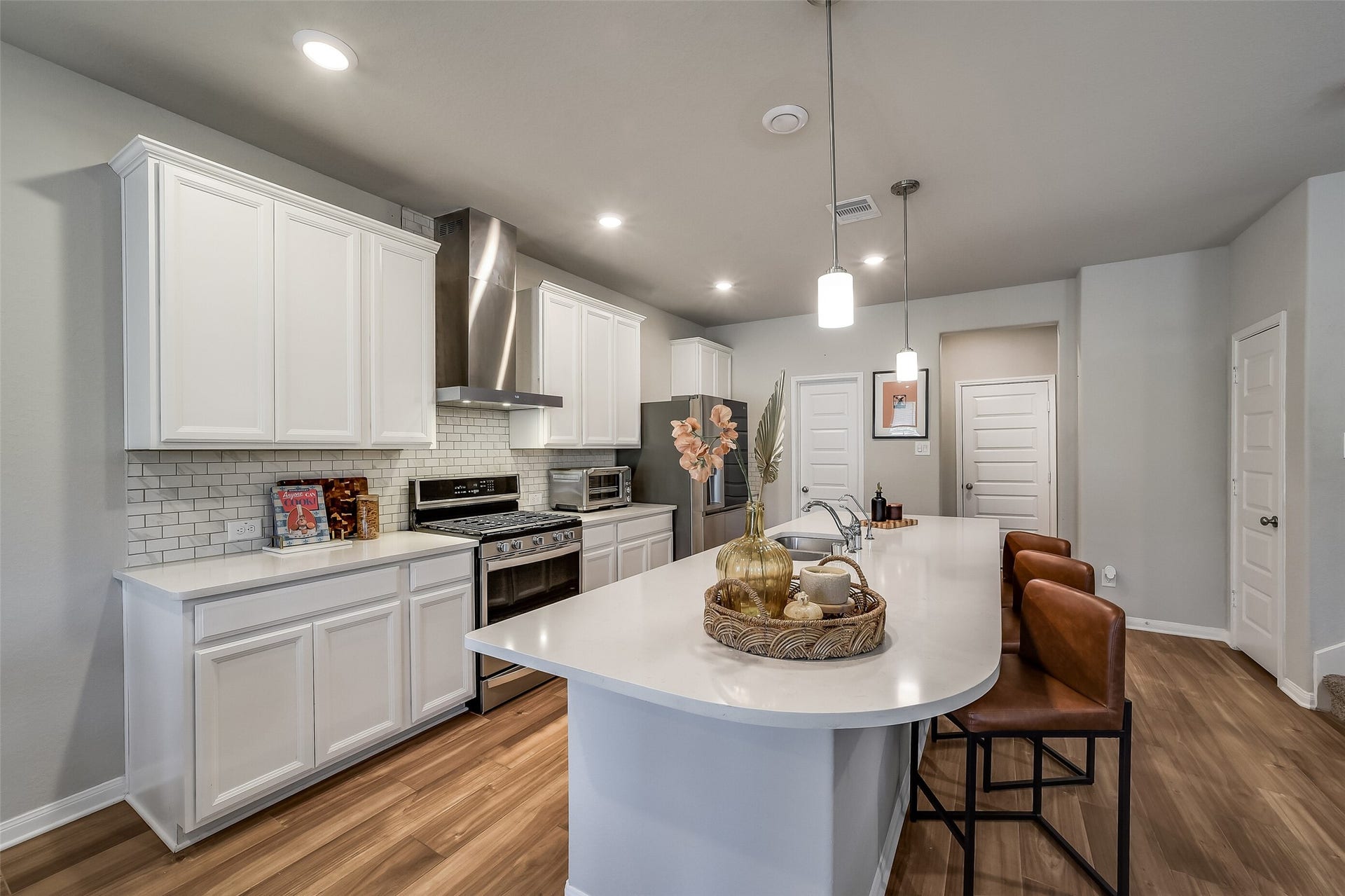 White cabinetry, light countertops, and a subway tile backsplash give the kitchen a fresh, cohesive feel, with an island providing additional workspace and seating.