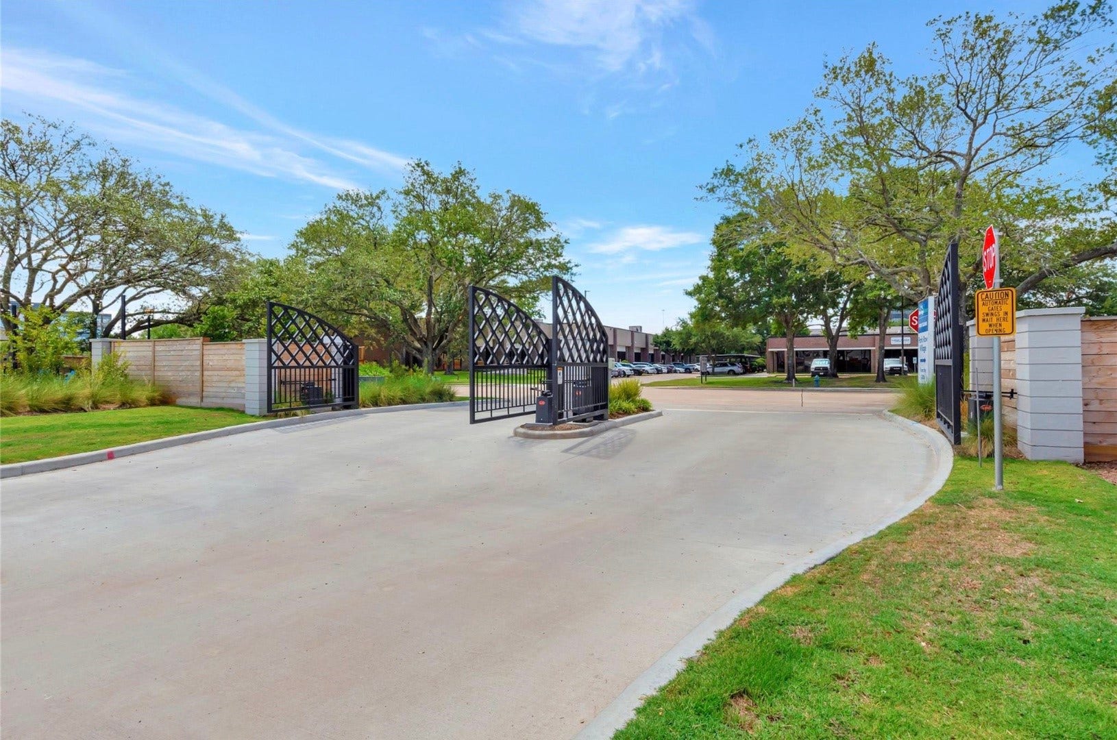 The gated vehicle entrance welcomes you into Park Row Village, with landscaped surroundings lining the approach.