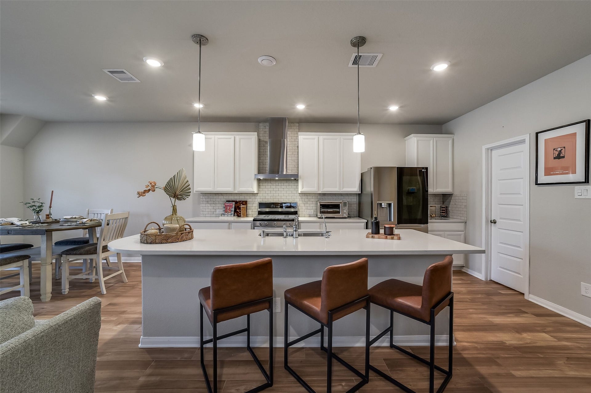 Pull up a seat for morning coffee or conversation at the generous kitchen island, complemented by pendant lighting and white cabinetry.