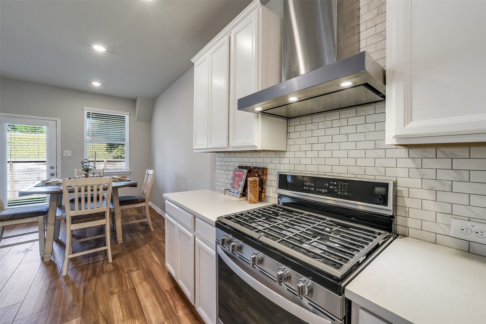 A gas range and a NEW stainless steel vent hood anchor the cooking area, with nearby counter space keeping meal preparation within easy reach.