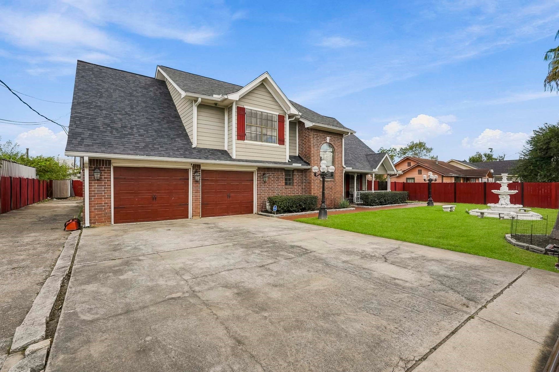1207 9th Street, Galena Park, TX 77547 Spacious two-story brick home with a three-car garage, charming front porch, and manicured lawn featuring a decorative fountain.