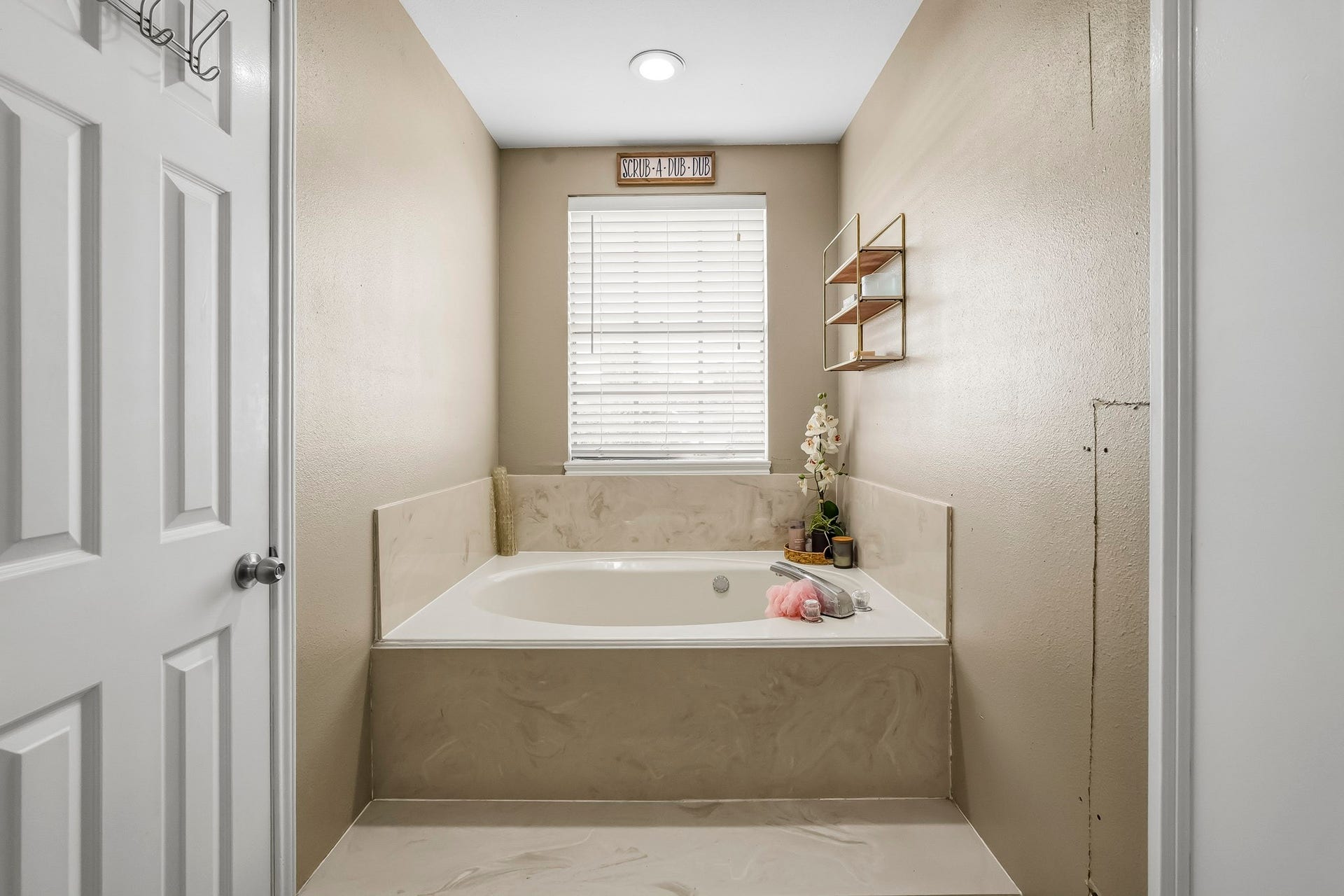 1207 9th Street, Galena Park, TX 77547 Relax in this serene bathroom featuring a spacious soaking tub set against neutral walls, with a window providing soft natural light.