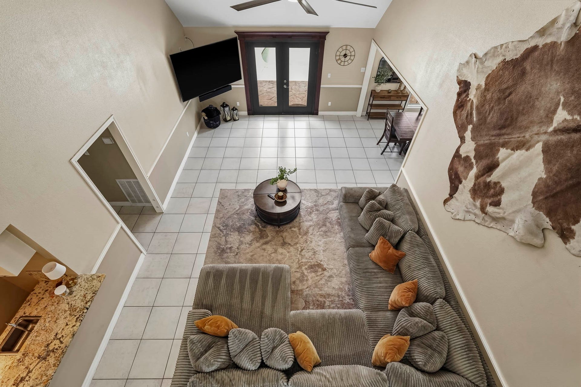 1207 9th Street, Galena Park, TX 77547 Spacious living area with high ceilings, featuring a cozy sectional sofa and modern decor. Large double doors lead to a bright and inviting outdoor space.