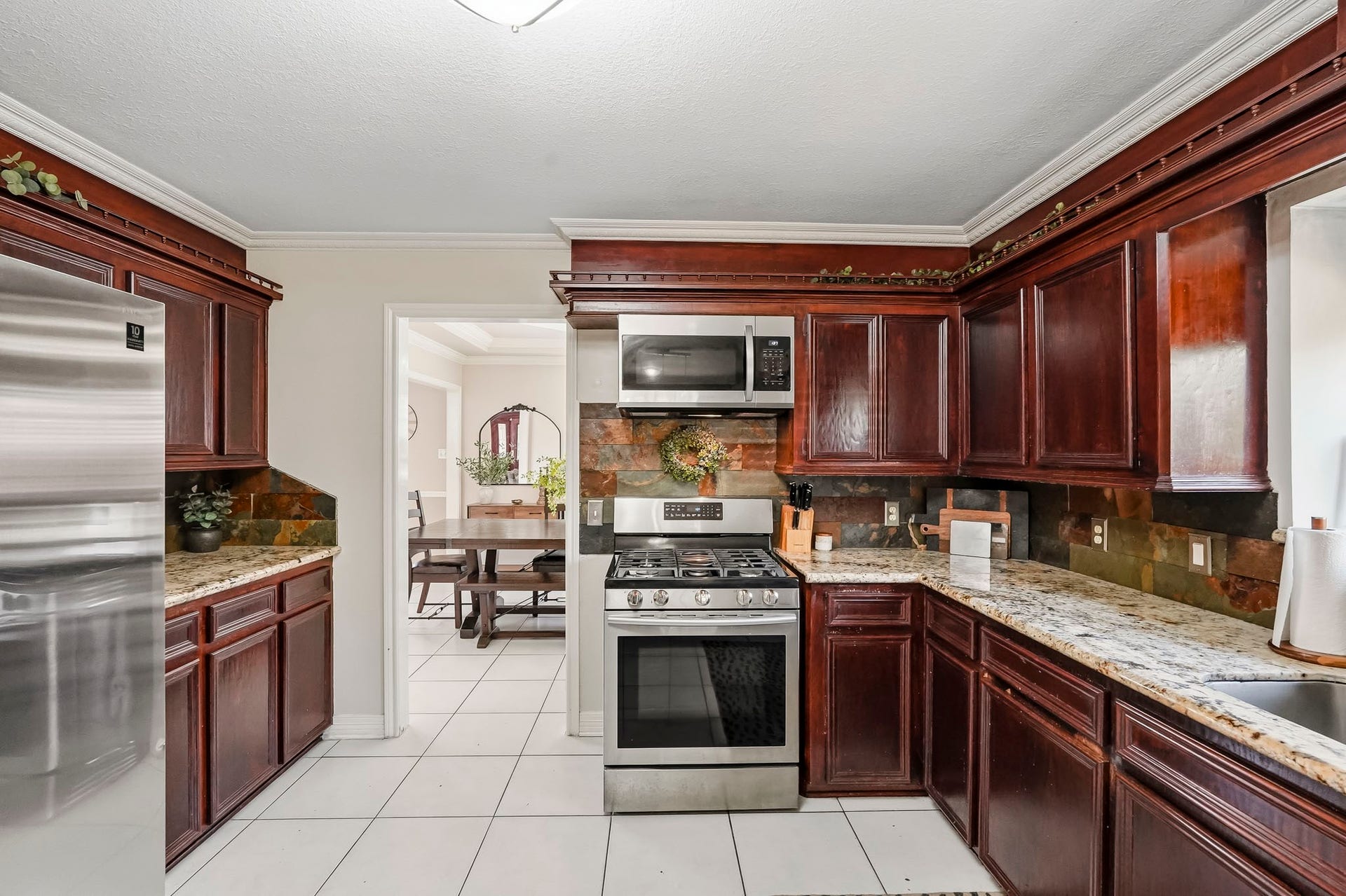 1207 9th Street, Galena Park, TX 77547 Elegant kitchen featuring rich wood cabinetry, sleek stainless steel appliances, and granite countertops, with a view into the inviting dining area.