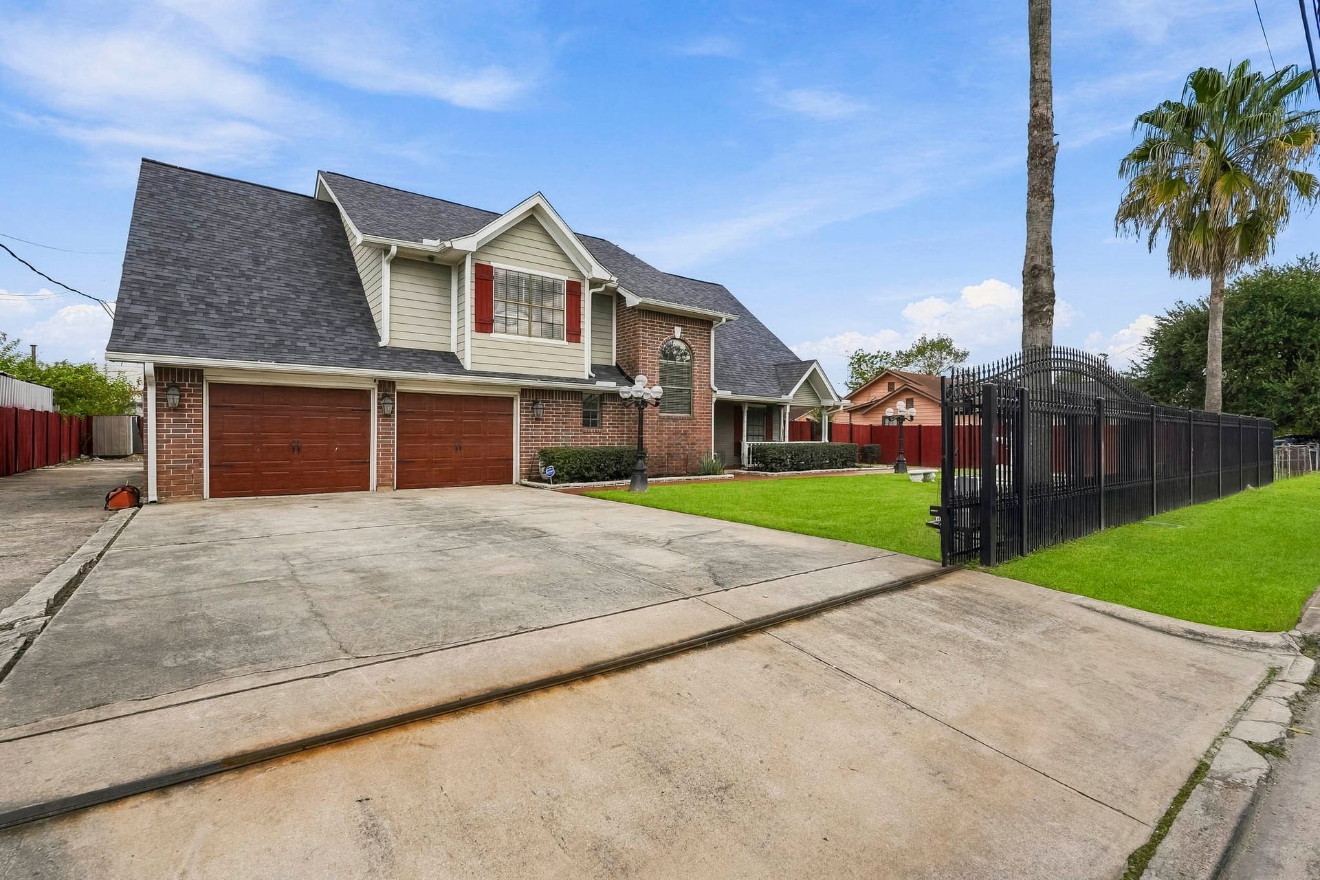 1207 9th Street, Galena Park, TX 77547 Stunning brick home featuring a spacious driveway leading to a two-car garage, complemented by a well-manicured lawn and secure gated entry.