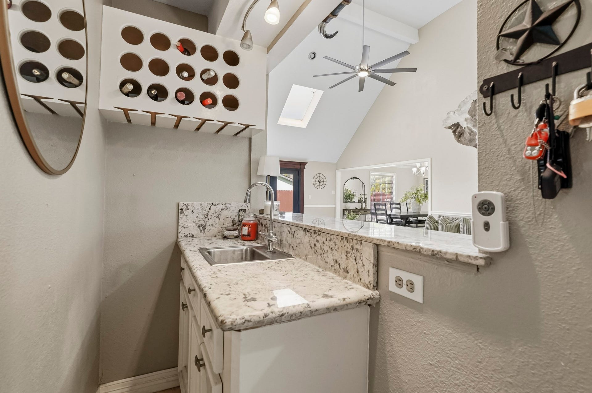 1207 9th Street, Galena Park, TX 77547 Charming wet bar area with granite countertops, wine storage, and a modern sink, seamlessly opens to a bright living space with vaulted ceilings and skylights.