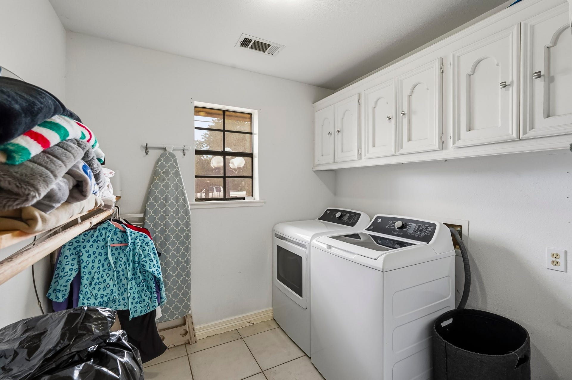 1207 9th Street, Galena Park, TX 77547 Spacious laundry room with modern washer and dryer, ample storage in overhead cabinets, and convenient hanging space.