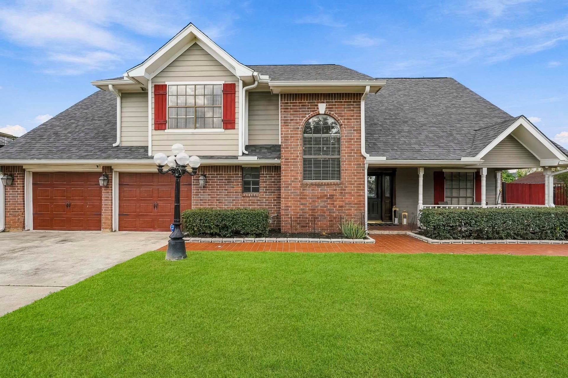 1207 9th Street, Galena Park, TX 77547 Charming two-story home with a classic brick facade, featuring a spacious two-car garage and inviting front porch. The well-maintained lawn and elegant lamp post enhance curb appeal.