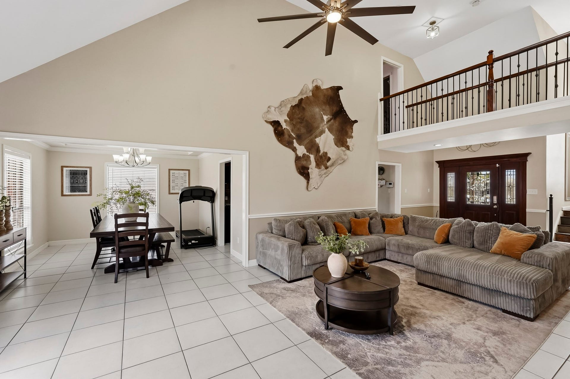 1207 9th Street, Galena Park, TX 77547 Spacious open-concept living area with high ceilings, featuring a cozy sectional sofa, elegant dining space, and a stylish balcony overlooking the room.