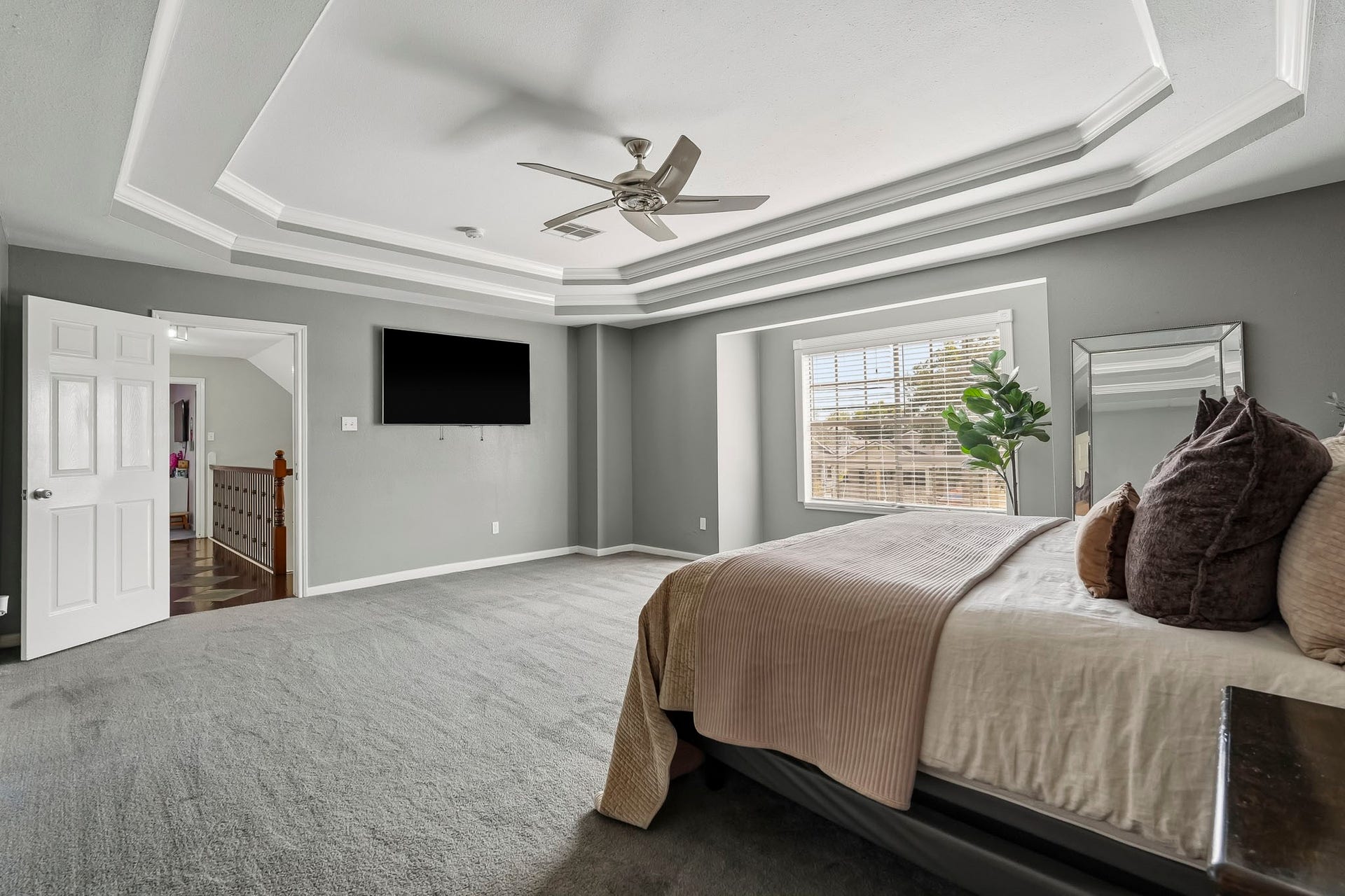 1207 9th Street, Galena Park, TX 77547 Spacious primary bedroom featuring a stylish tray ceiling, plush carpeting, and abundant natural light from a large window.
