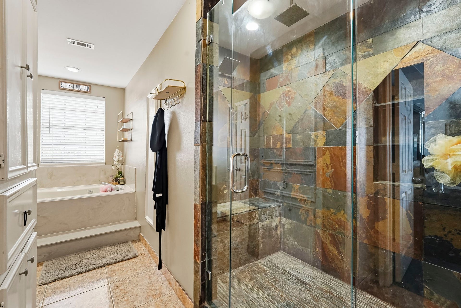 1207 9th Street, Galena Park, TX 77547 Luxurious bathroom featuring a spacious walk-in shower with unique slate tile design and a serene soaking tub bathed in natural light.