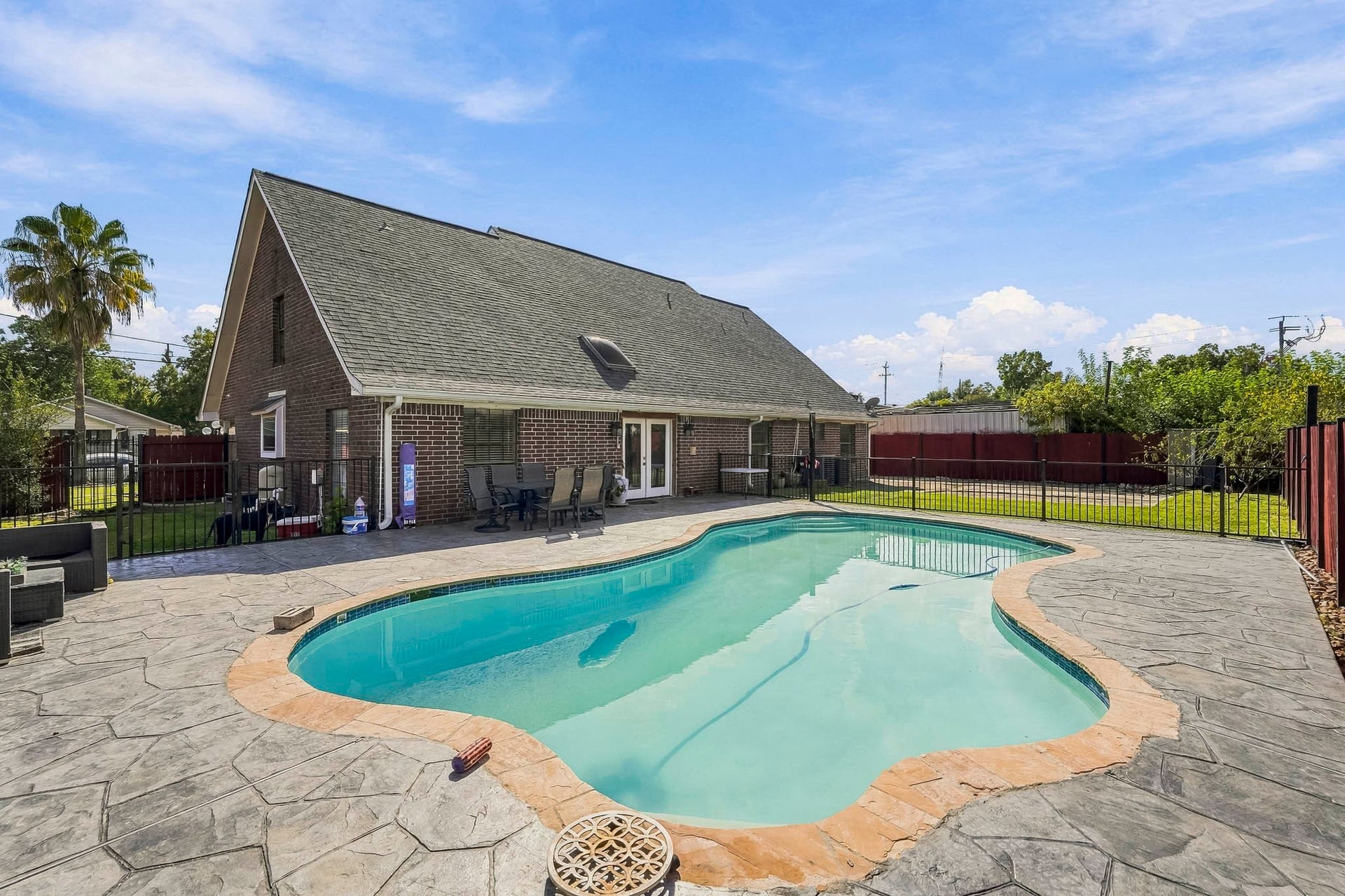1207 9th Street, Galena Park, TX 77547 Spacious backyard oasis featuring a sparkling pool, expansive patio, and a charming brick home, perfect for entertaining and relaxation.
