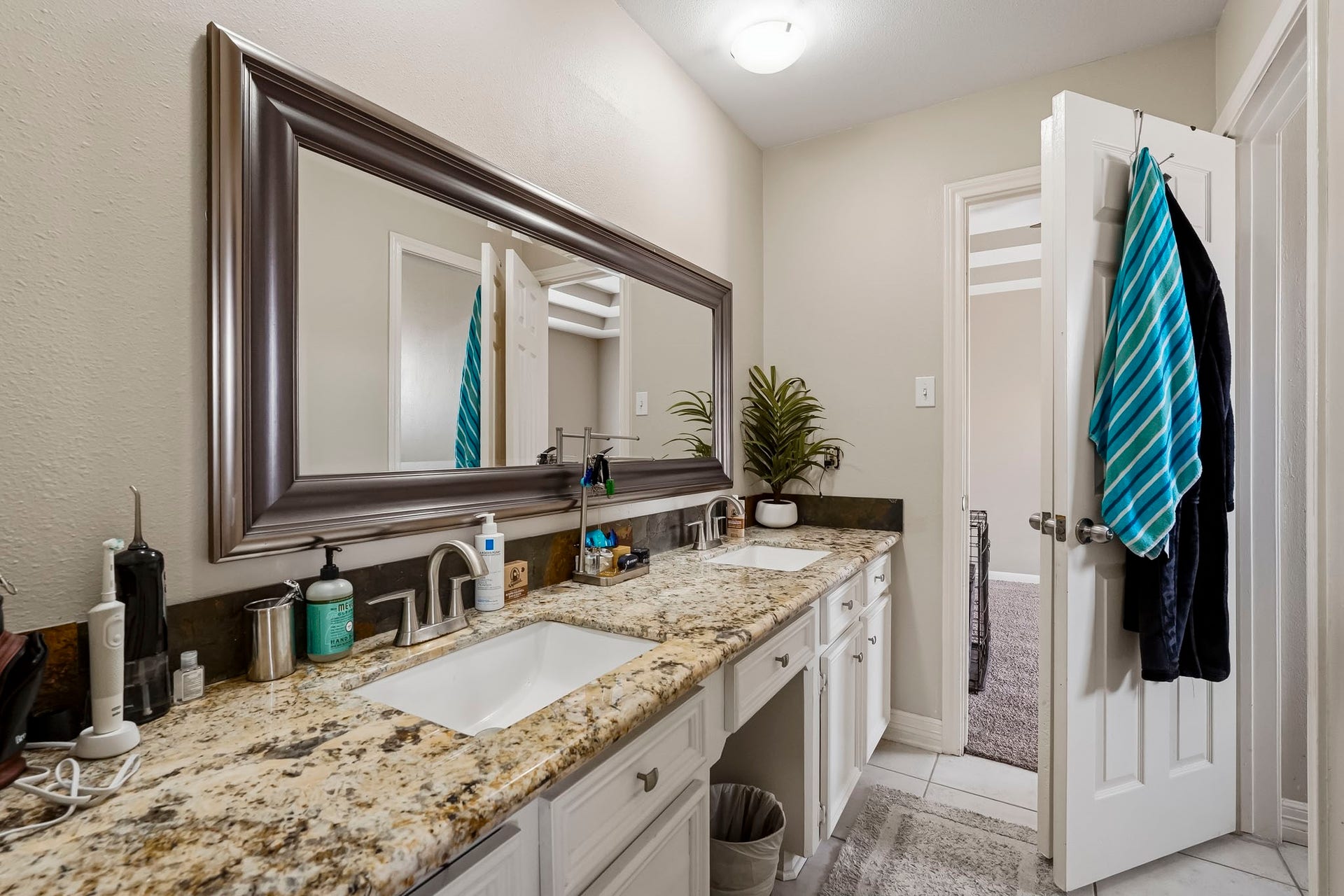 1207 9th Street, Galena Park, TX 77547 Elegant secondary bathroom featuring a granite countertop with dual sinks, modern fixtures, and ample storage, complemented by a large framed mirror.