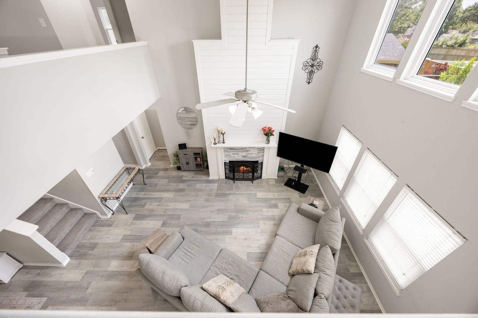 3915 Eastland Lake Drive, Richmond, TX 77406 A view from the second-floor catwalk highlights the expansive family room footprint below, showcasing the floor-to-ceiling fireplace surround and the open arrangement connecting to the upper level.
