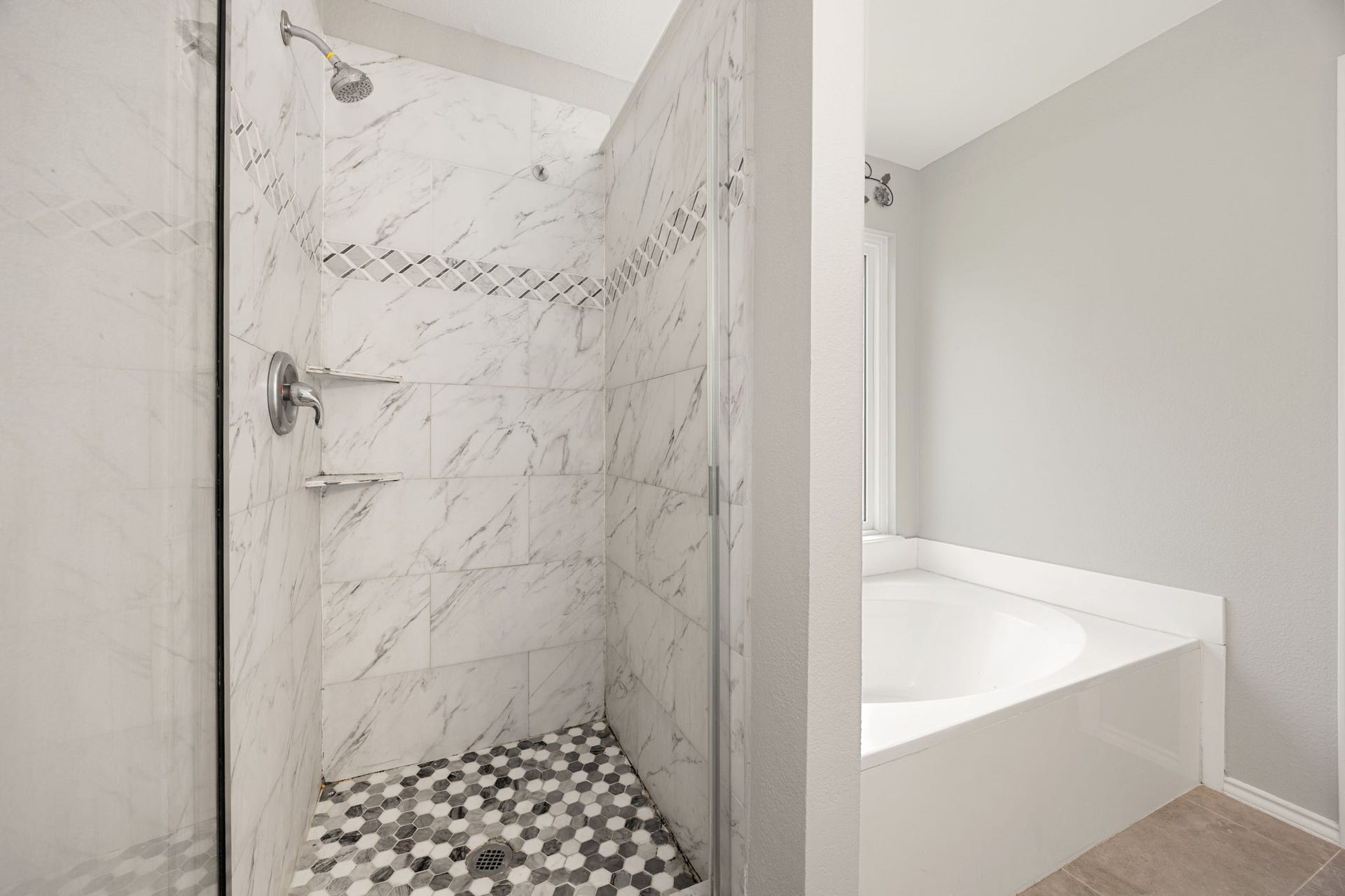 3915 Eastland Lake Drive, Richmond, TX 77406 The primary bathroom includes a custom walk-in shower lined with refined marble-patterned tile and geometric mosaic floor tiling.