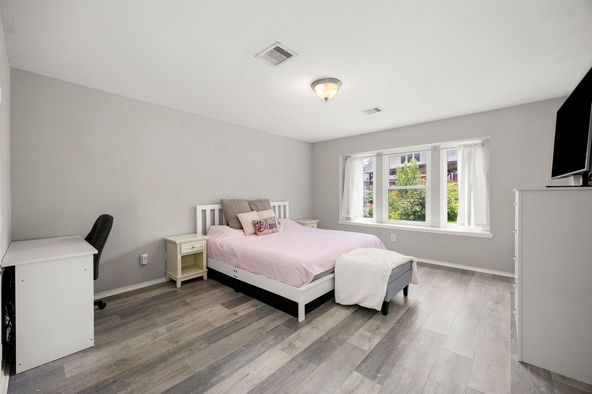 3915 Eastland Lake Drive, Richmond, TX 77406 This first-floor primary suite features durable flooring, neutral gray walls, a dedicated workspace area, and a large triple window that brings in comfortable views.