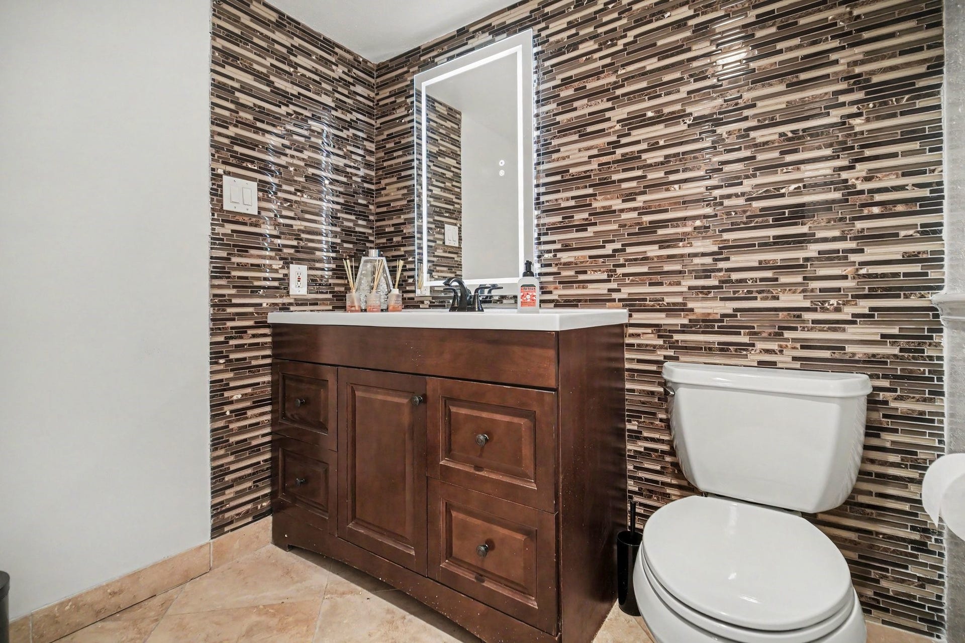 Elegant half bath featuring a sleek modern backsplash, stylish vanity, and contemporary fixtures for a touch of sophistication.
