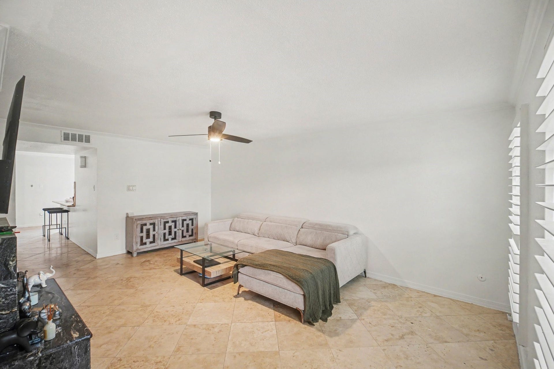 Discover a bright and inviting living area featuring elegant tile flooring, a cozy sectional sofa, and modern accents, perfect for relaxation and entertaining.