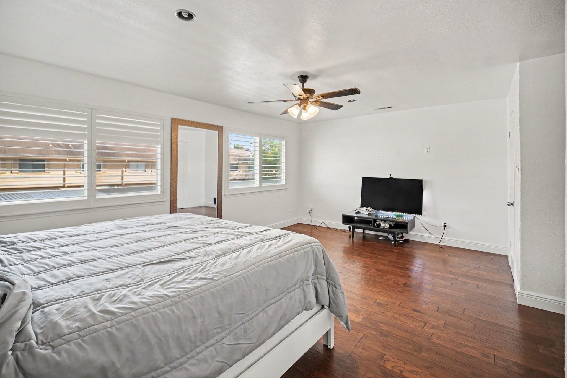 Spacious and inviting, the primary bedroom boasts abundant natural light, sleek hardwood floors, and a ceiling fan for ultimate comfort.